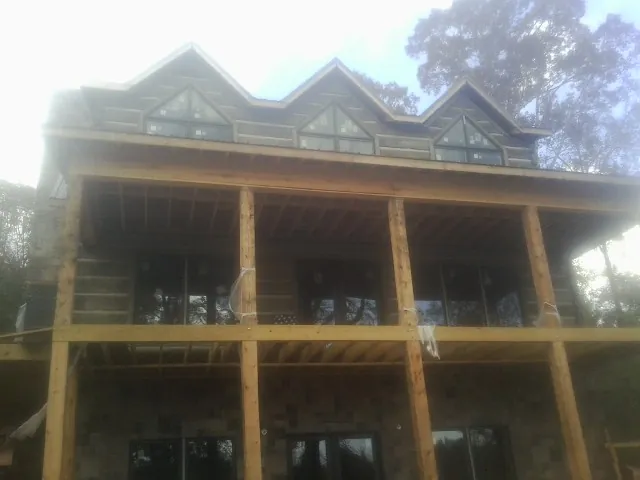 Dormers and porch framing on a large log home under construction — Roof Coating work by our crew in Saxapahaw