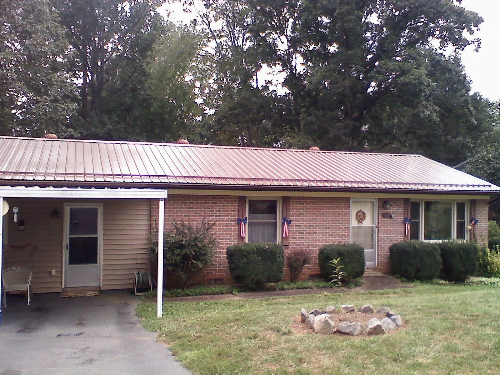 Bronze metal roof and carport on a brick ranch home — Roof Repair work by our crew in Saxapahaw