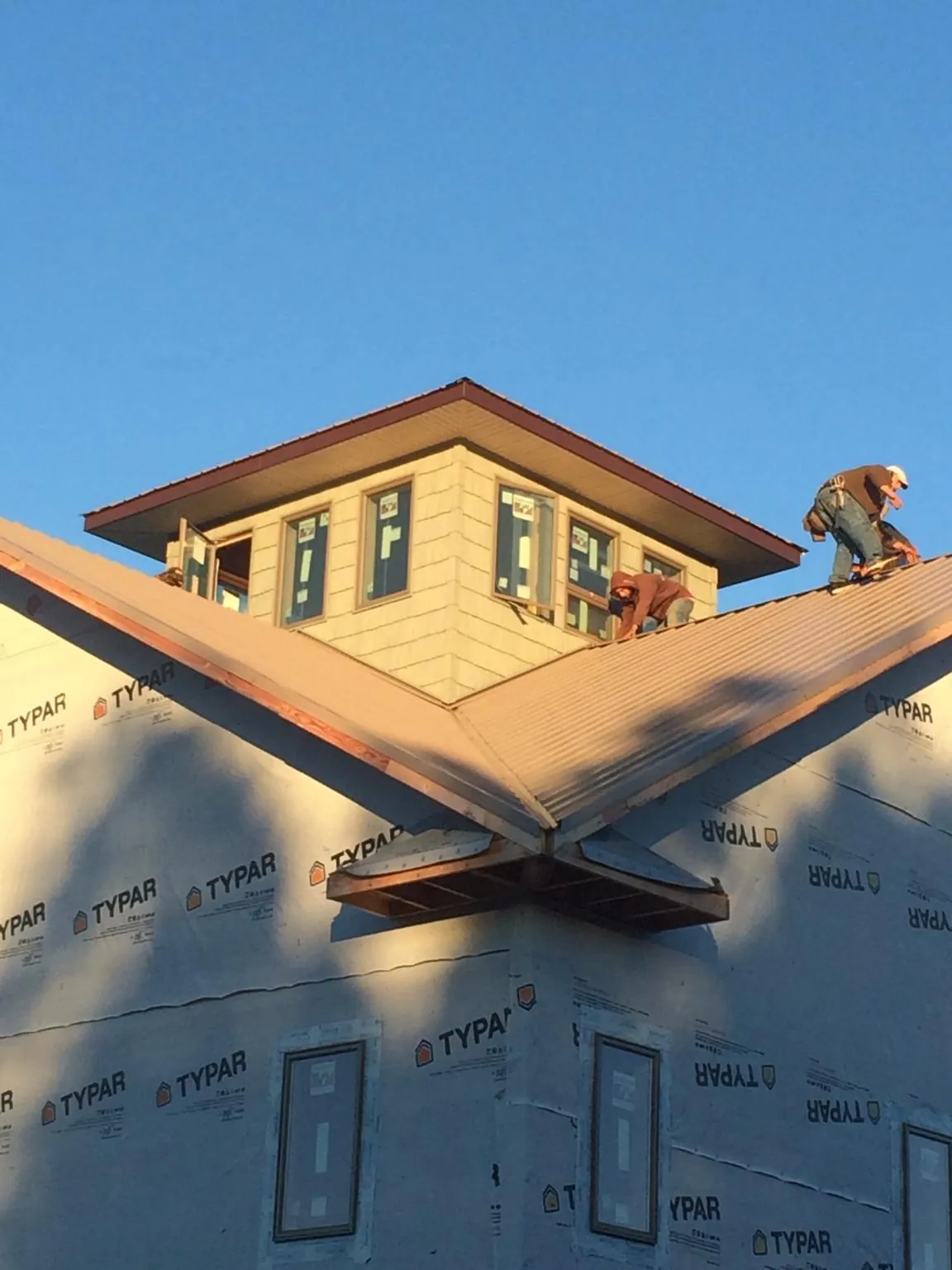 Roofers working around a rooftop cupola on a new metal roof at sunset — Roof Waterproofing in Saxapahaw by Roofing Brothers